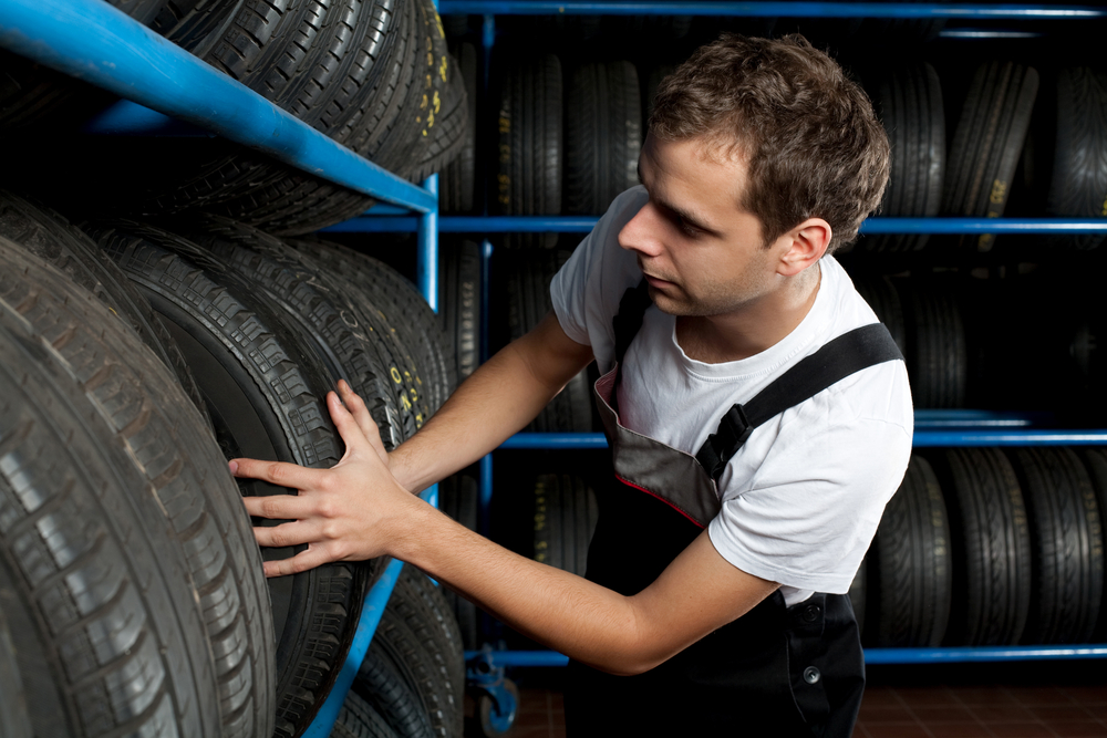Mladý mechanik vybírá pneumatiky v autoservisu
